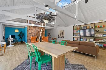 A room with a table and chairs in the foreground and a shelving unit in the background.